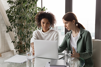 Two women staring at a laptop